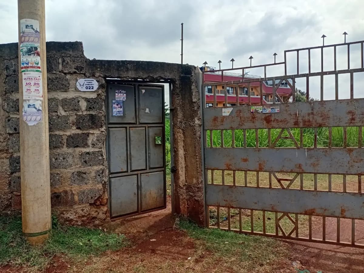 Compound entrance gate with metal door and perimeter fencing