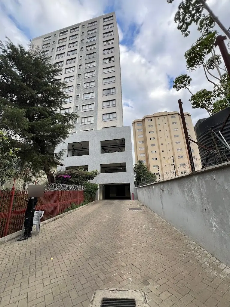 Multi-story residential tower with paved driveway and parking entrance
