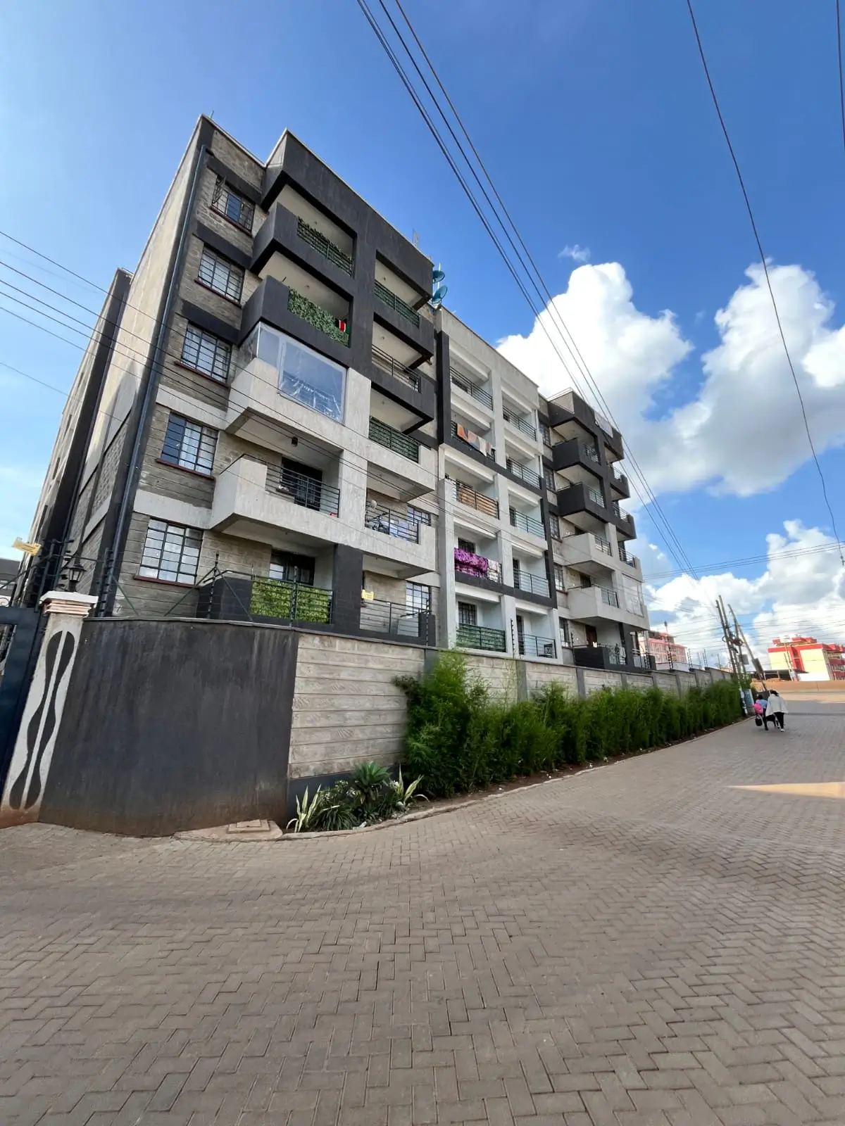 Modern multi-story residential building with landscaped compound entrance