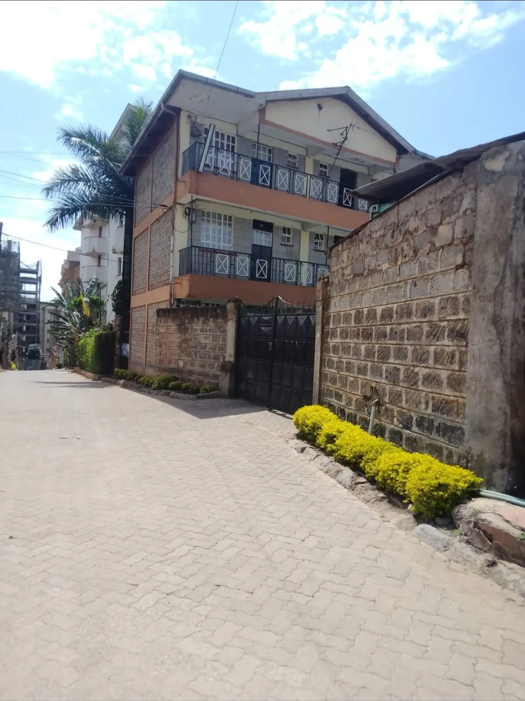 Multi-story residential building with paved compound and gate