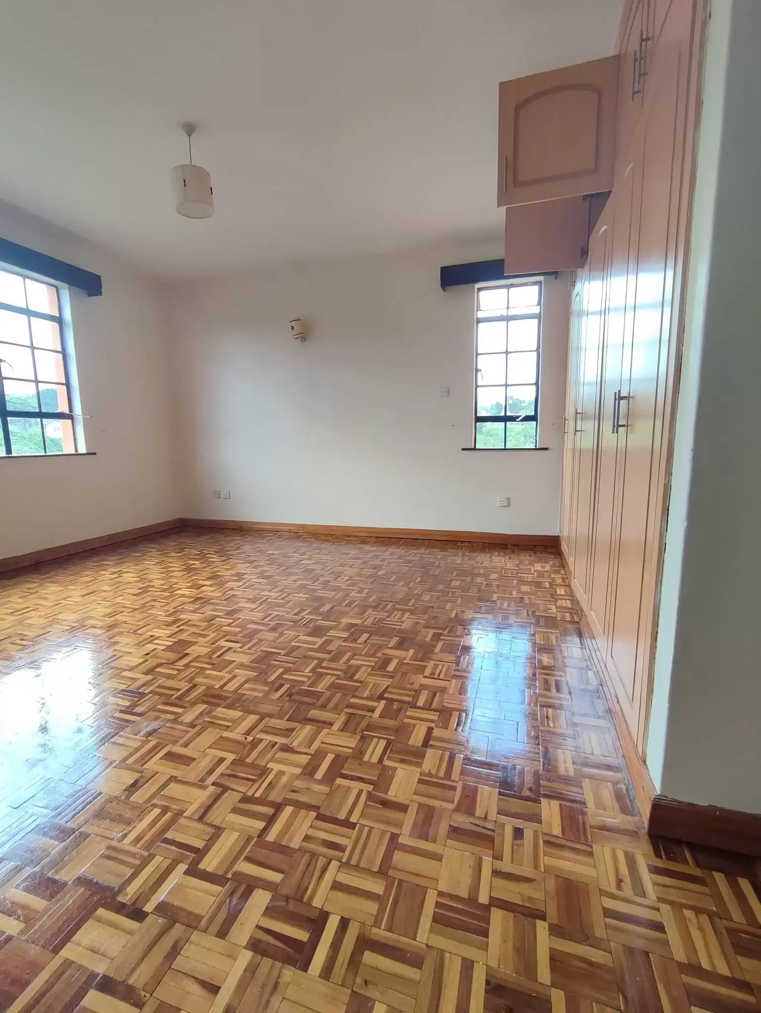 Spacious bedroom with parquet flooring and bright windows
