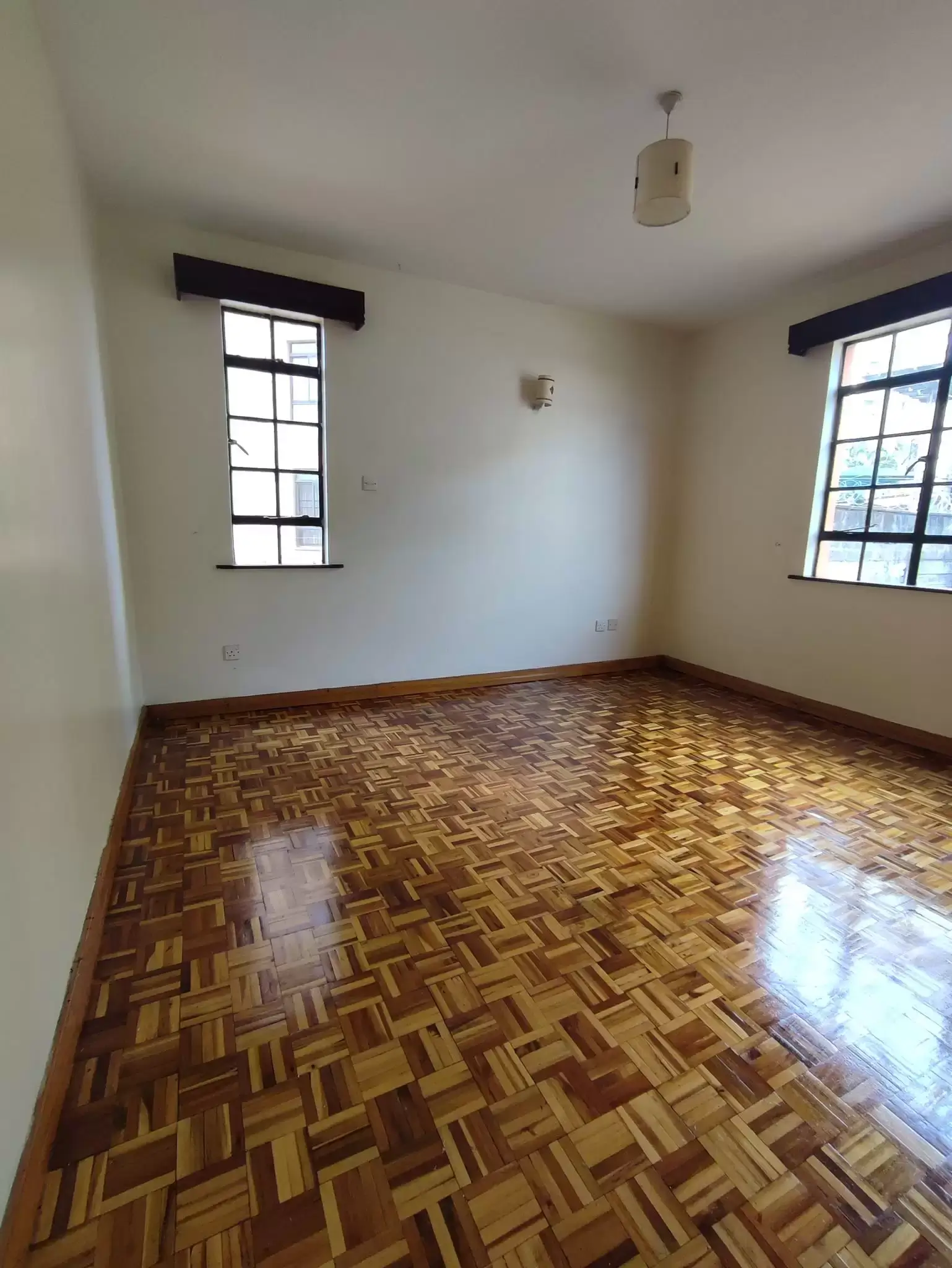 Spacious bedroom with wooden parquet flooring and natural light