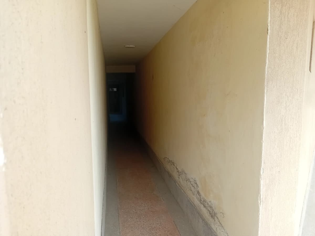 Narrow indoor corridor with cream walls and tiled floor