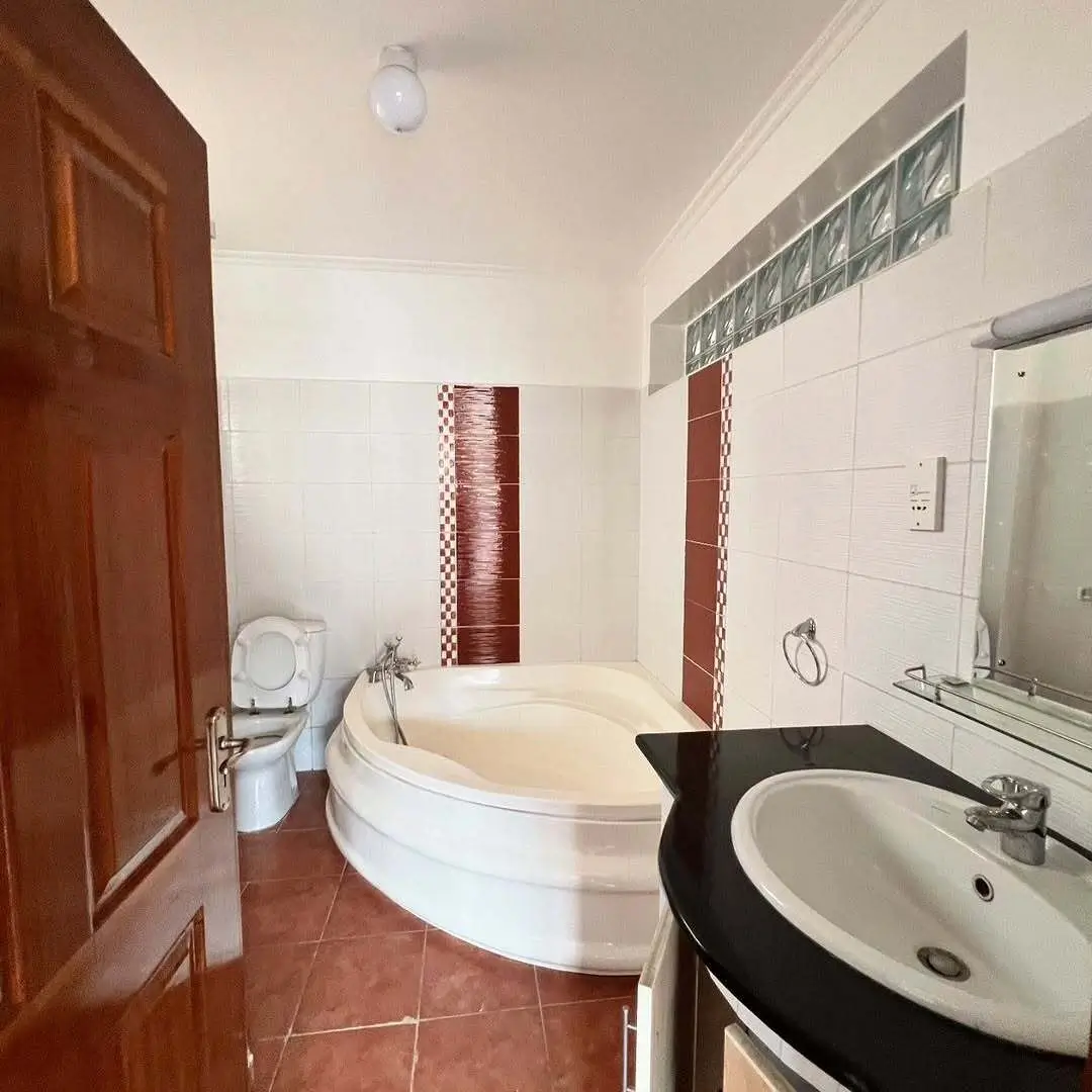 Spacious bathroom with corner bathtub and pedestal sink