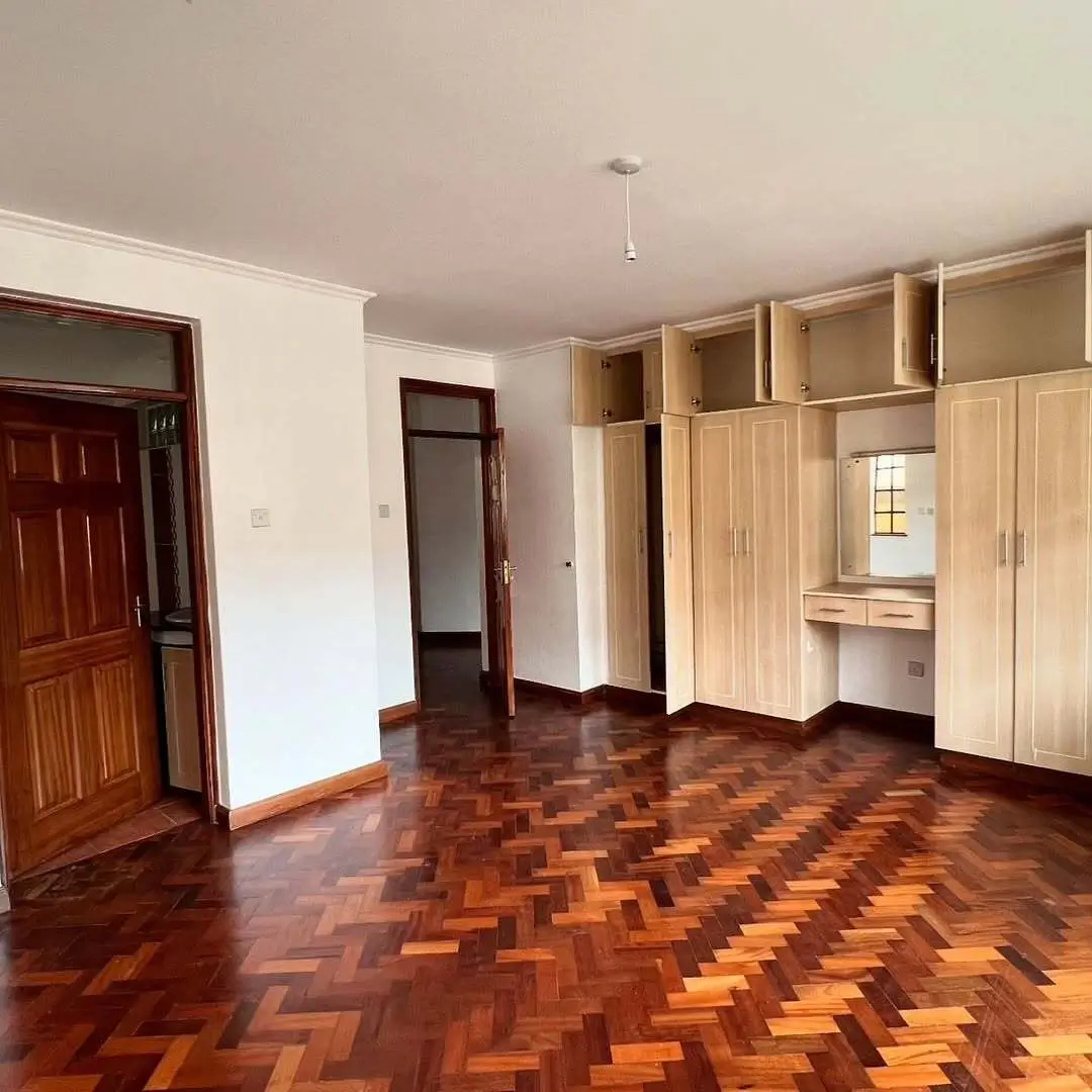 Spacious bedroom with herringbone wood flooring and built-in wardrobes