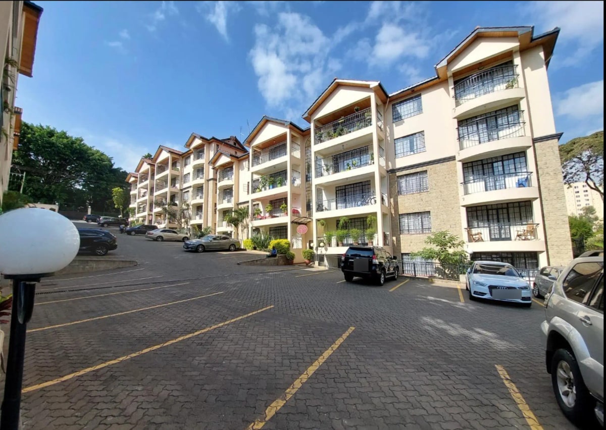 Multi-story residential complex with paved compound and parking bays