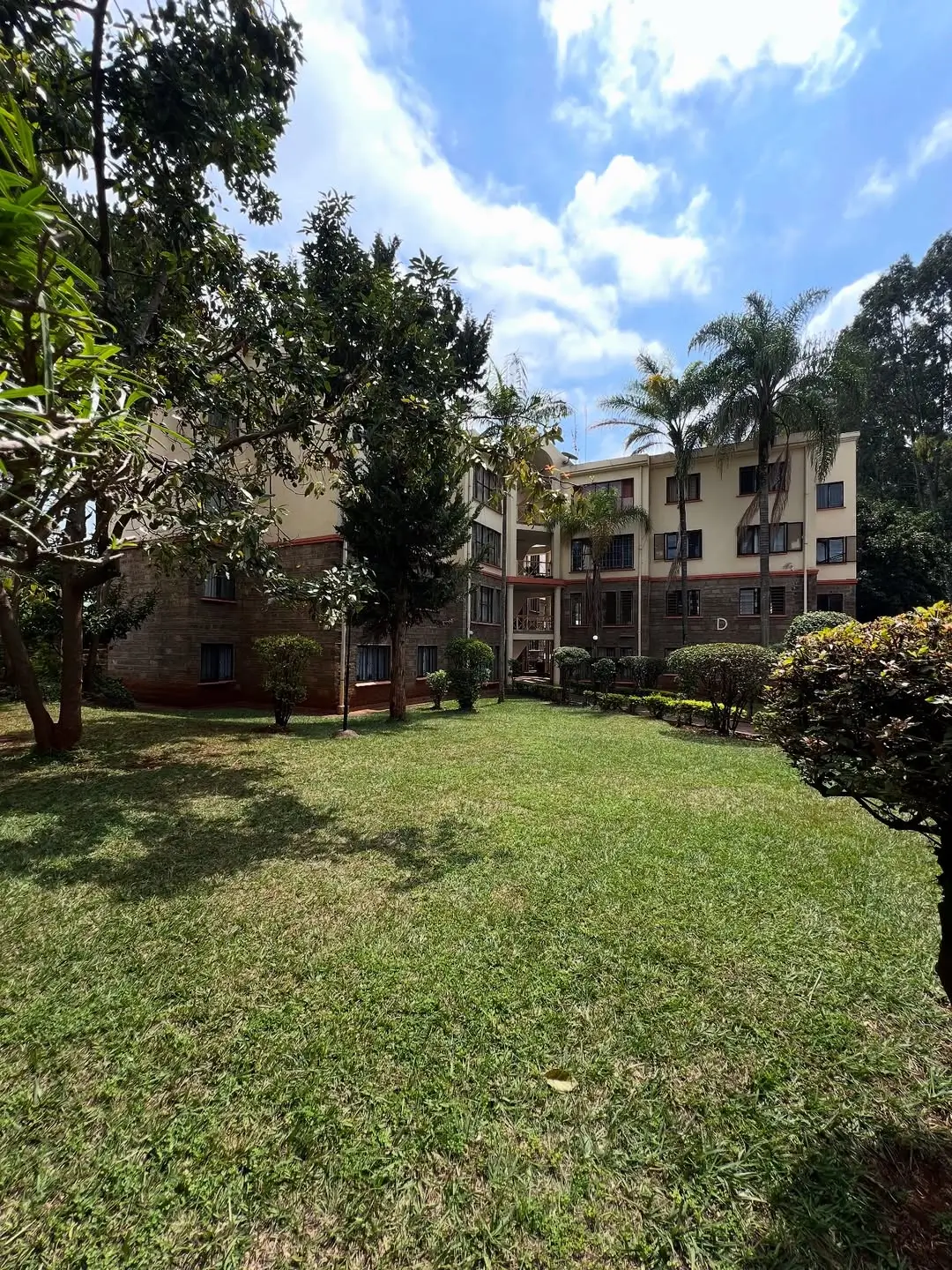 Lush manicured lawn with mature trees and building backdrop
