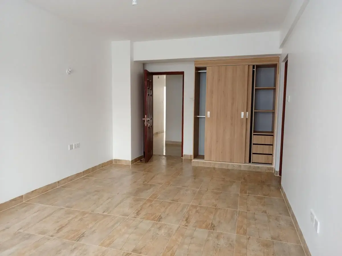 Spacious bedroom with wooden wardrobe and tiled flooring