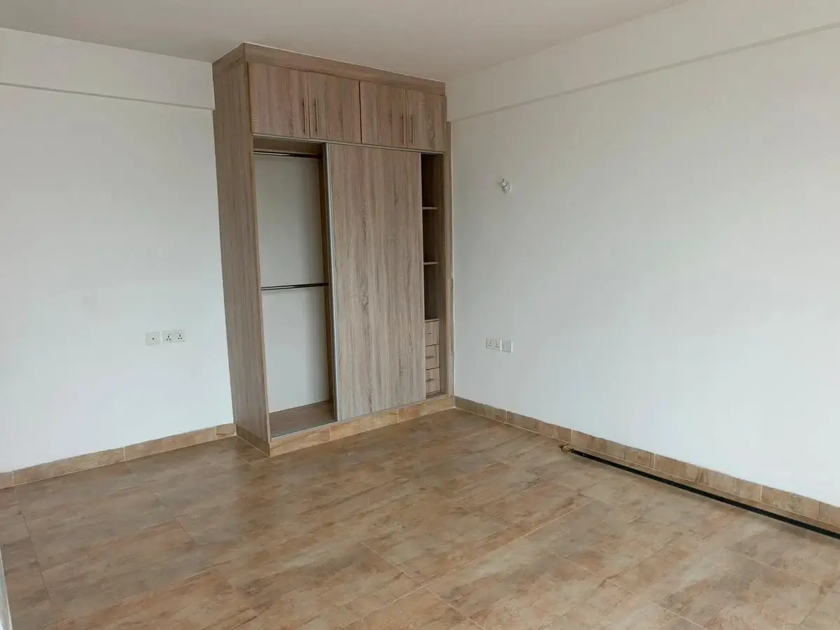 Unfurnished bedroom with wooden wardrobe and laminate flooring