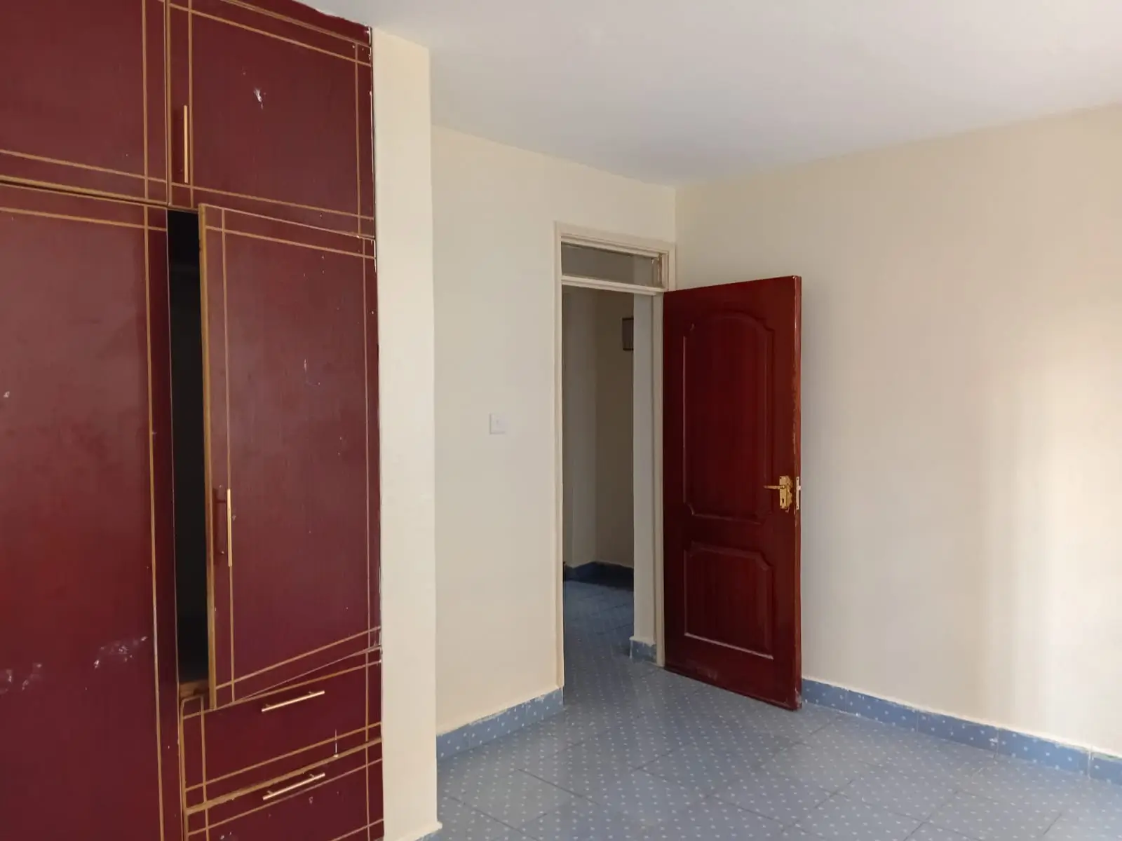 Empty bedroom with burgundy doors and blue flooring