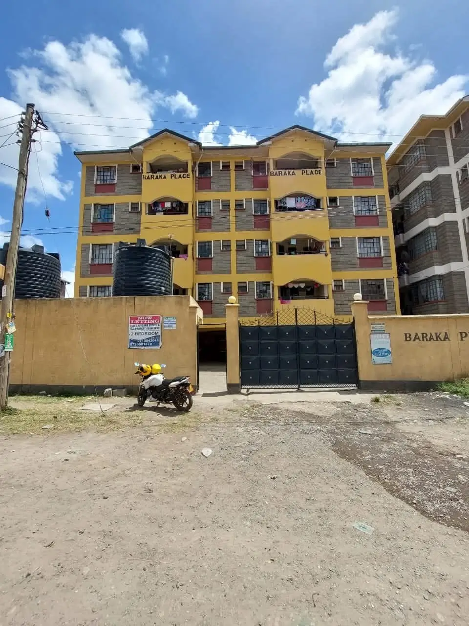 Yellow multi-story residential building with blue gate entrance