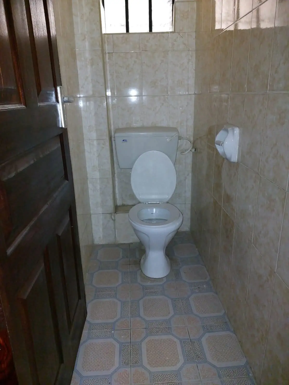 Compact bathroom with toilet, sink, and tiled flooring