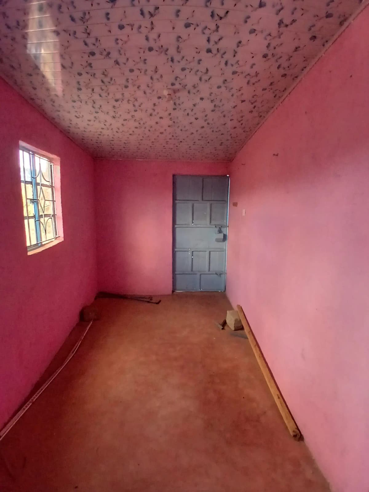 Empty bedroom with pink walls and speckled ceiling