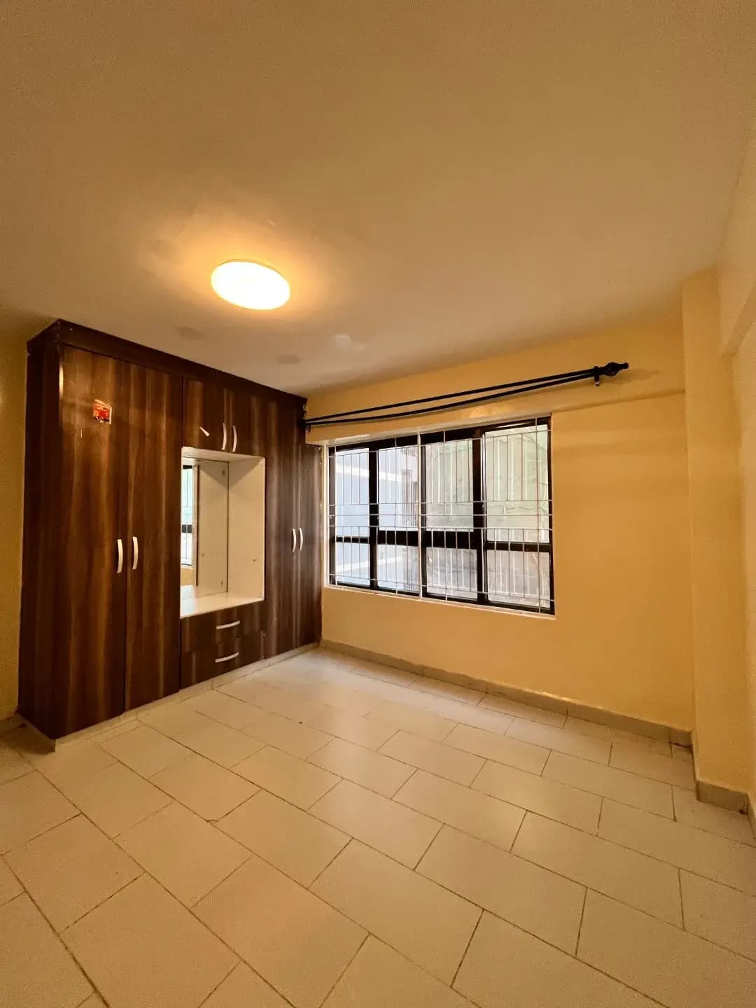Spacious bedroom with built-in wooden wardrobe and natural light