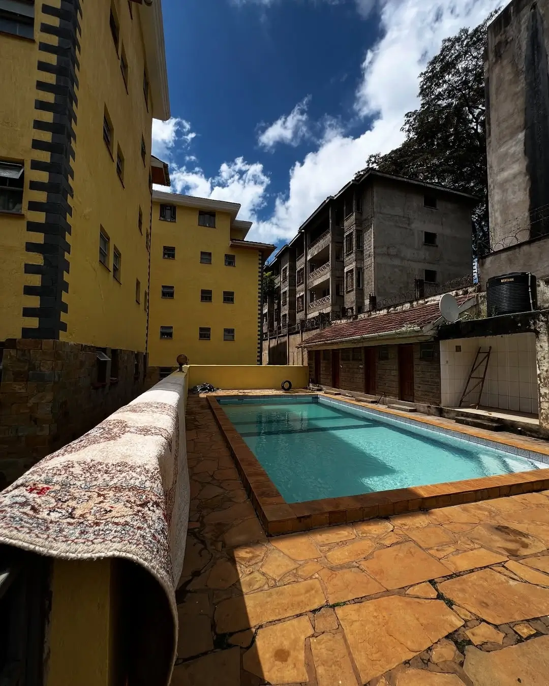 Residential swimming pool with terracotta deck and surrounding buildings