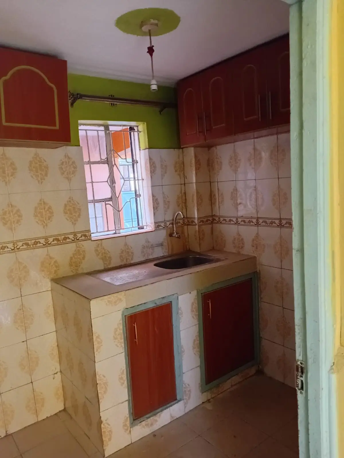 Compact kitchen with red cabinetry and tiled walls