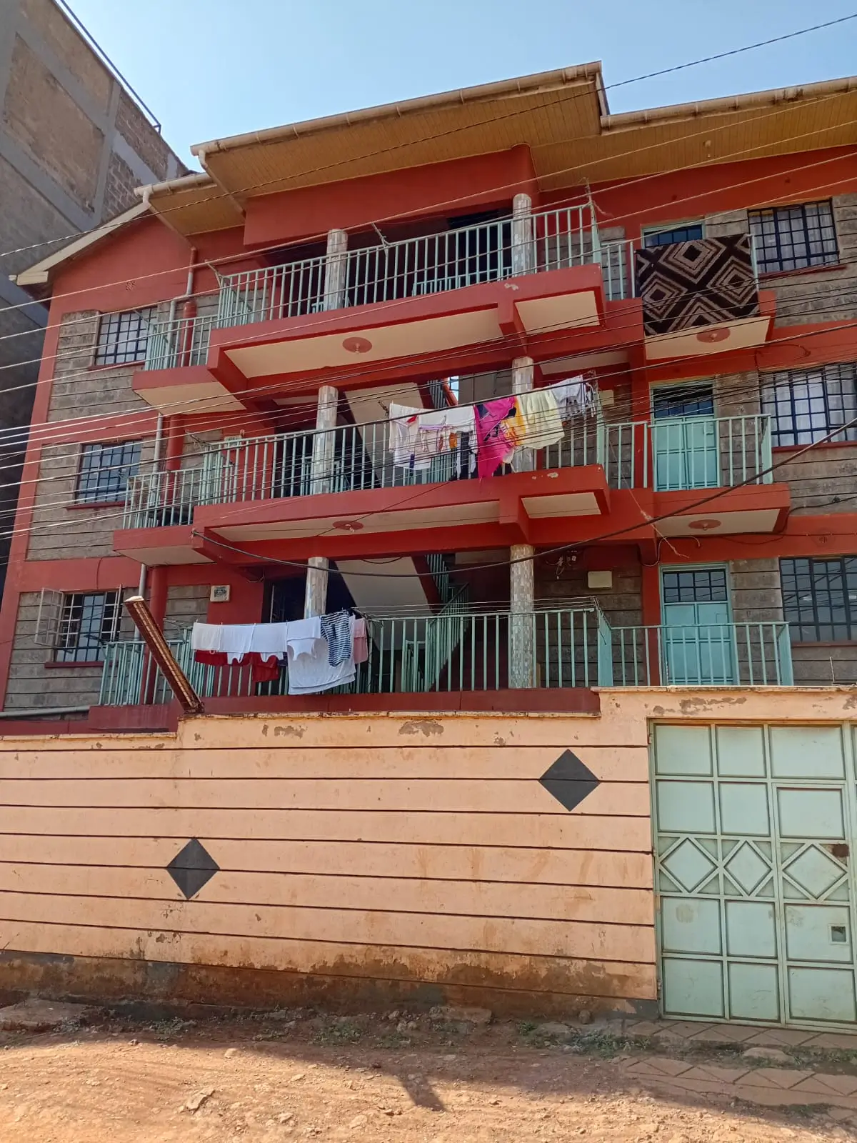 Red multi-story residential building with balconies and gate