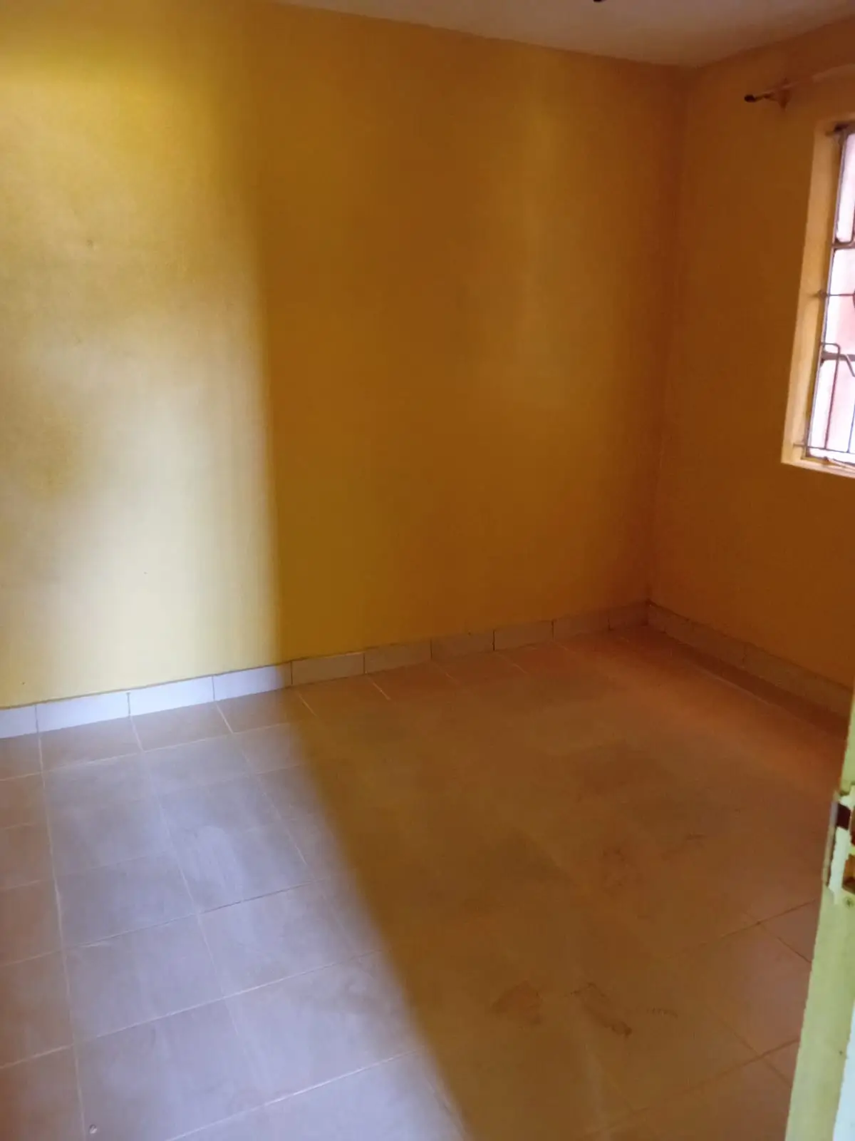 Empty bedroom with yellow walls and tiled flooring
