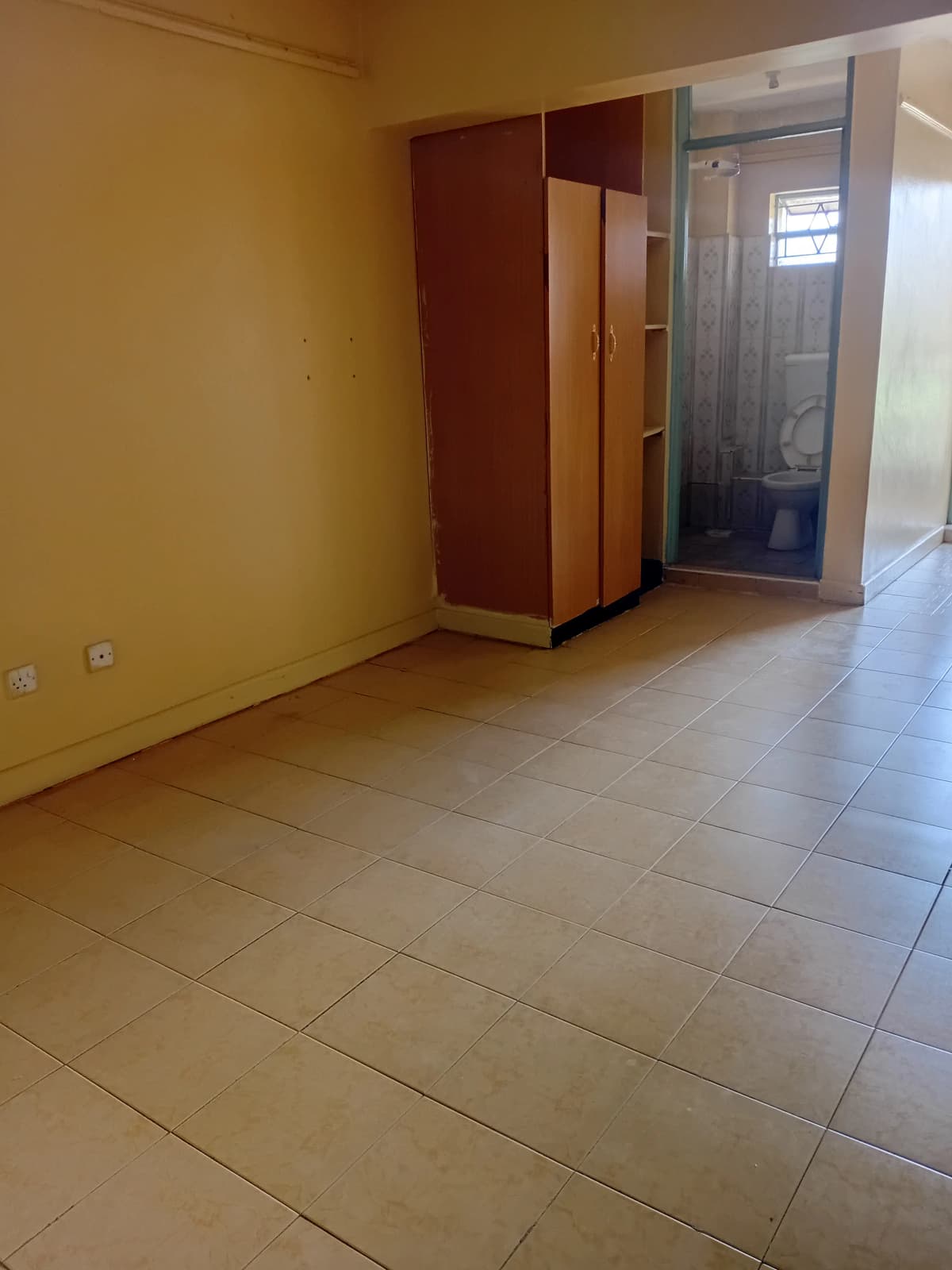 Empty living room with yellow walls and tiled flooring