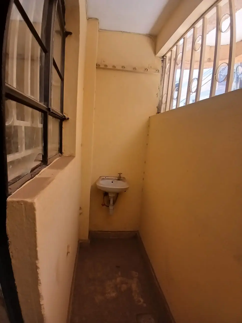 Small bathroom with wall-mounted sink and barred window