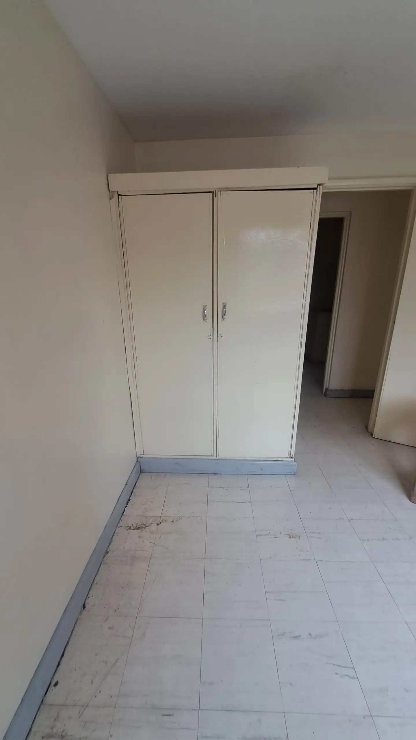 Empty bedroom with built-in wardrobe and tiled flooring
