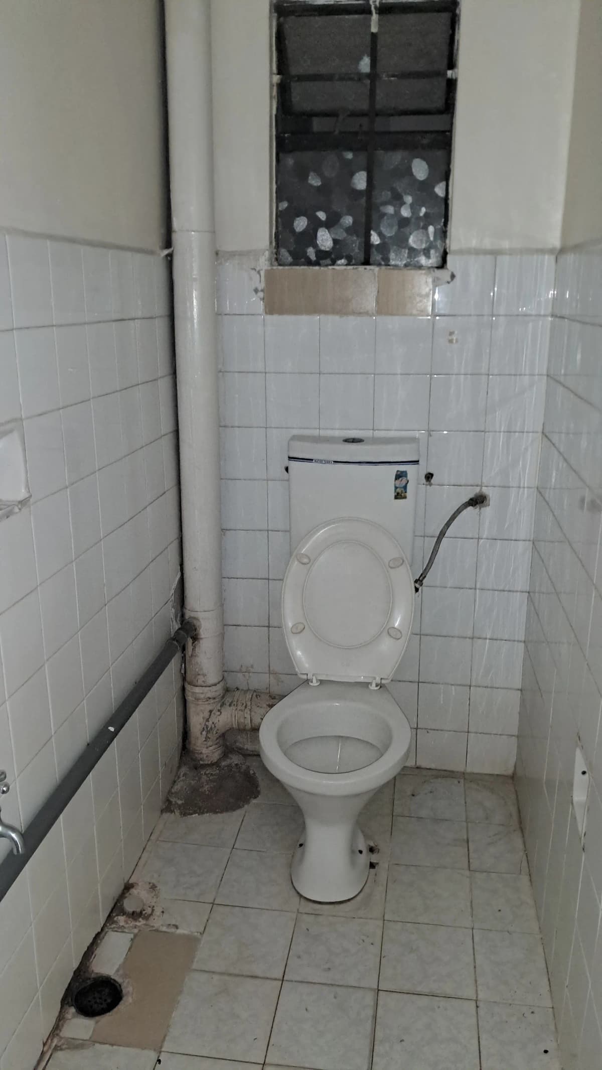 Basic toilet room with white tile walls and small window