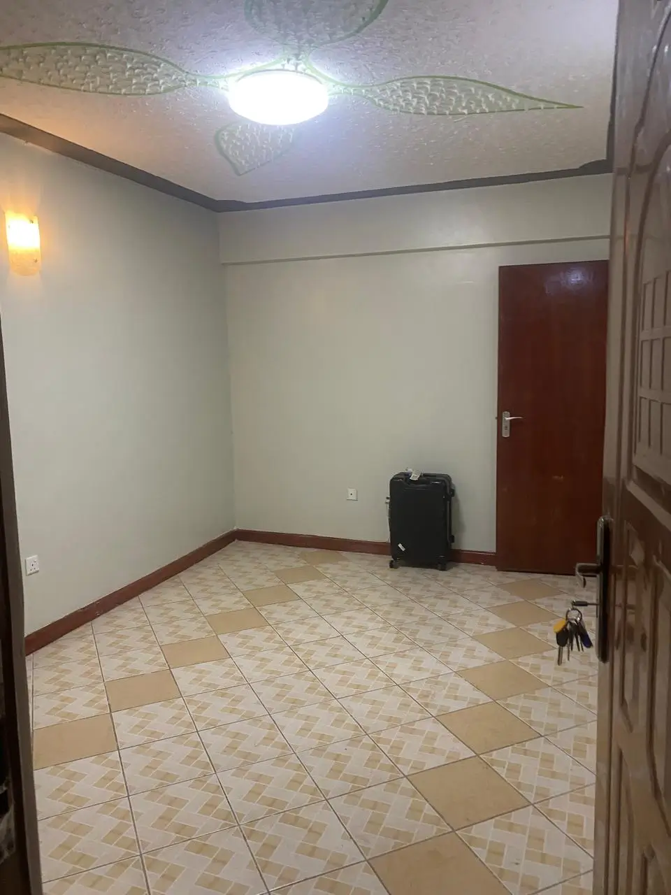 Empty bedroom with tiled floor and red door entry