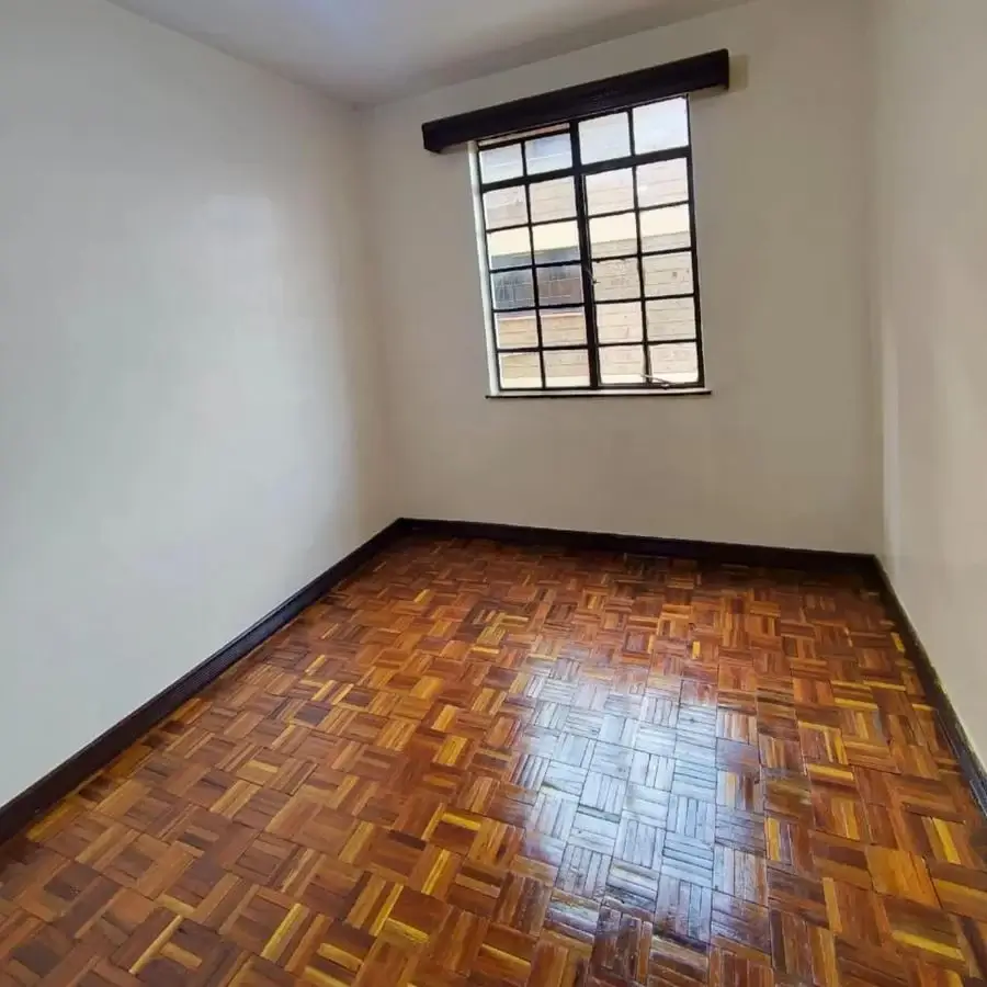 Empty bedroom with wooden parquet flooring and barred window