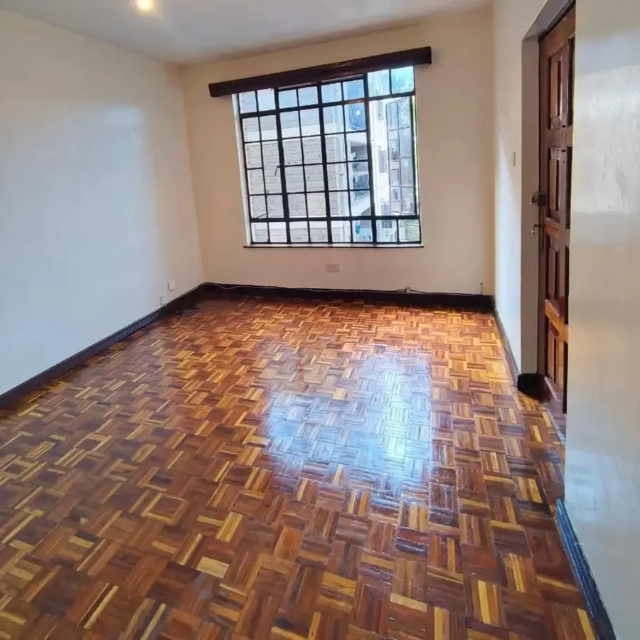 Spacious bedroom with wooden parquet floor and barred windows