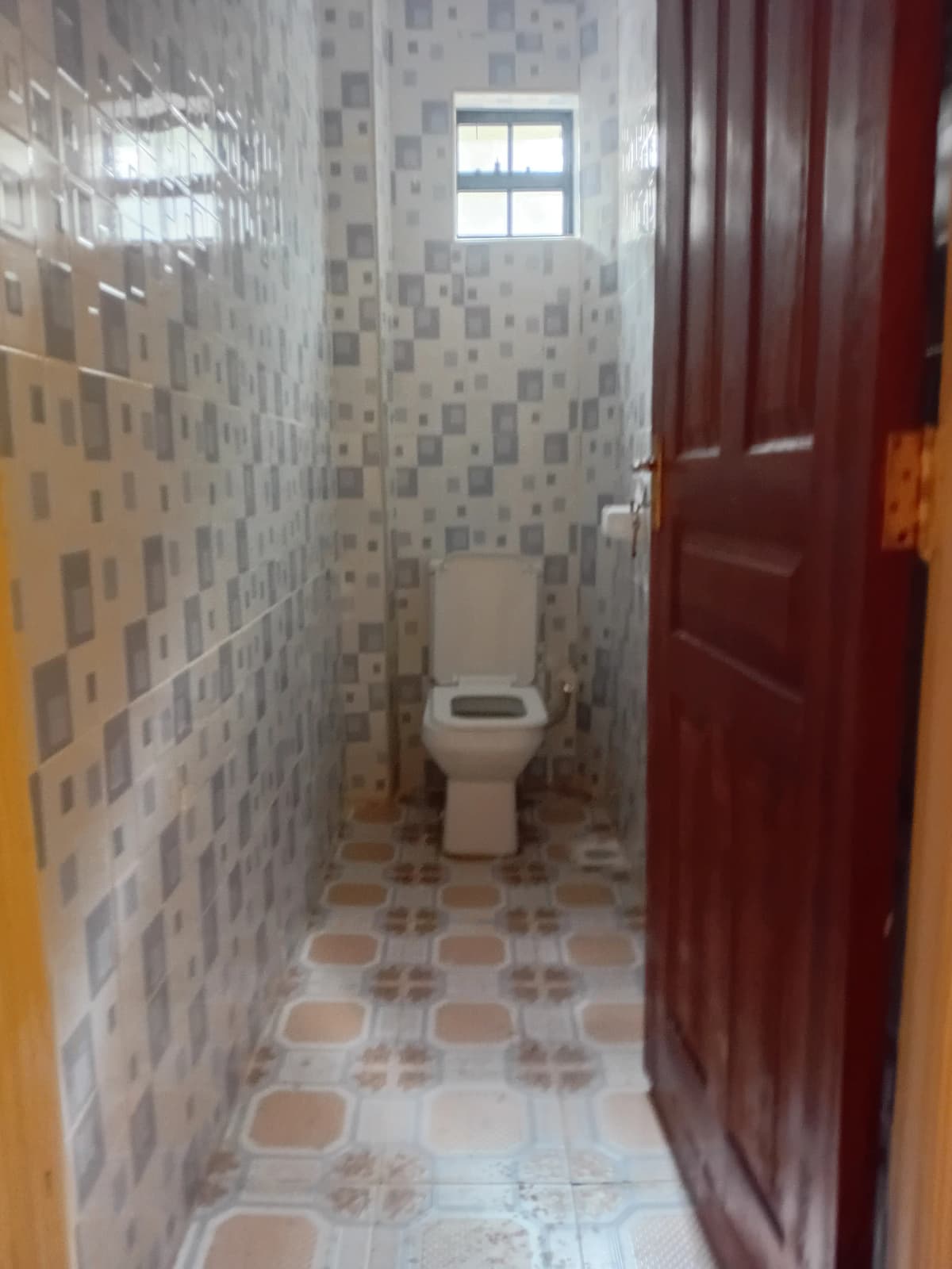 Compact bathroom with patterned tile walls and ceramic toilet
