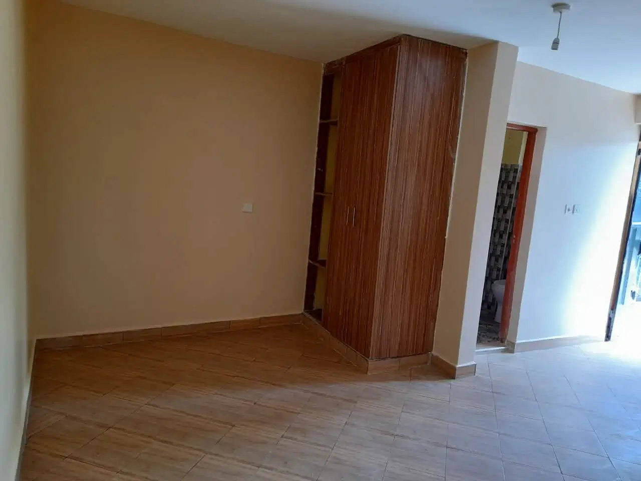 Spacious empty bedroom with wooden wardrobe and laminate flooring