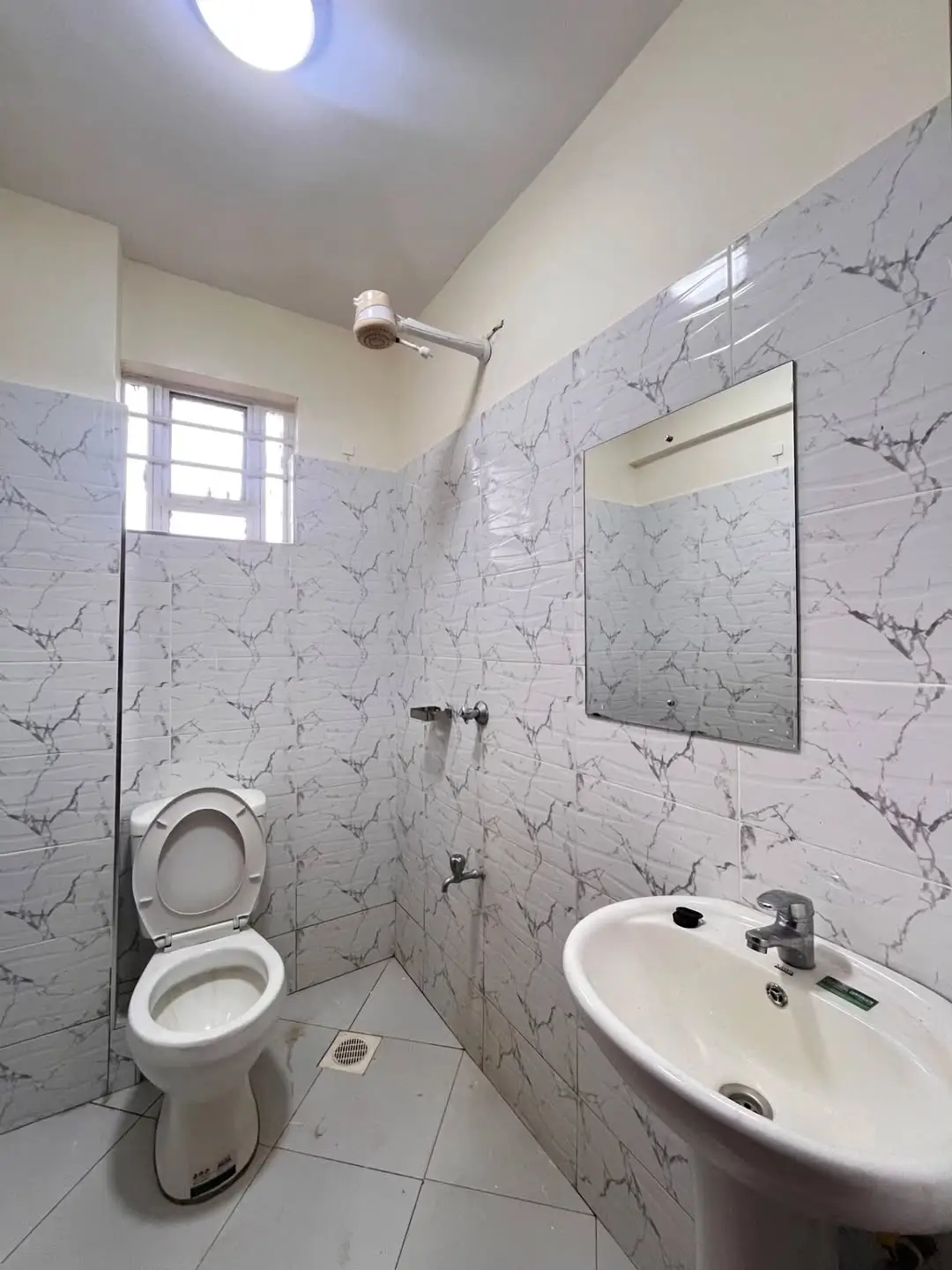 Modern bathroom with marble tiles, toilet, sink, mirror