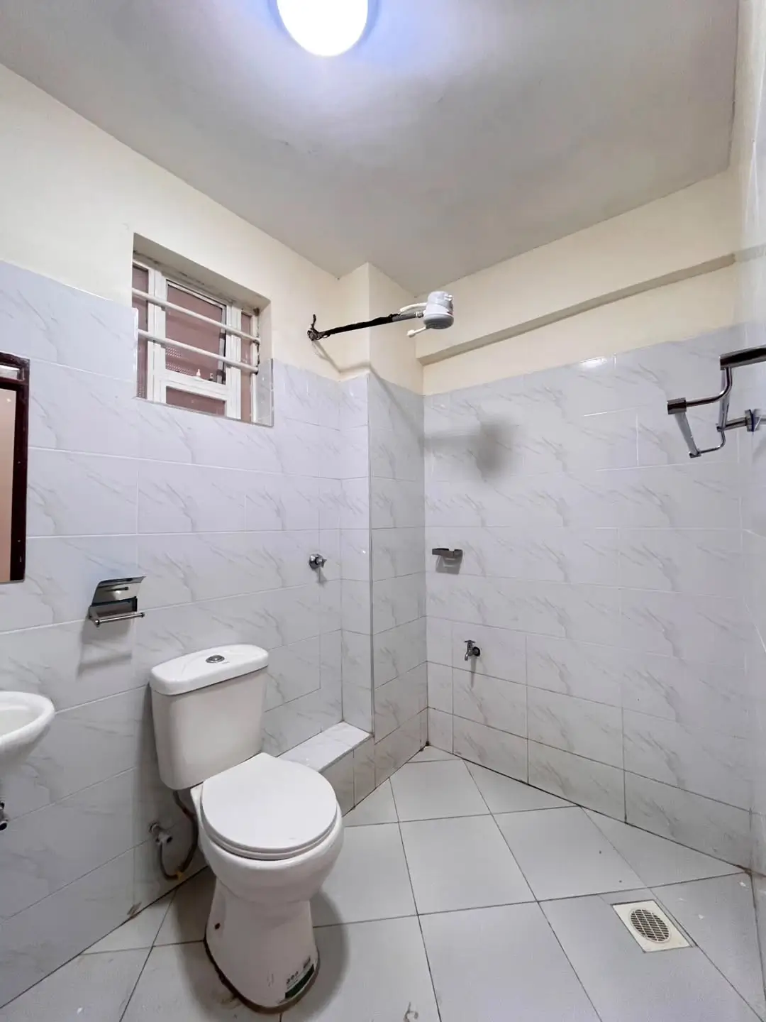 Modern bathroom with marble tiles, toilet, and glass shower enclosure