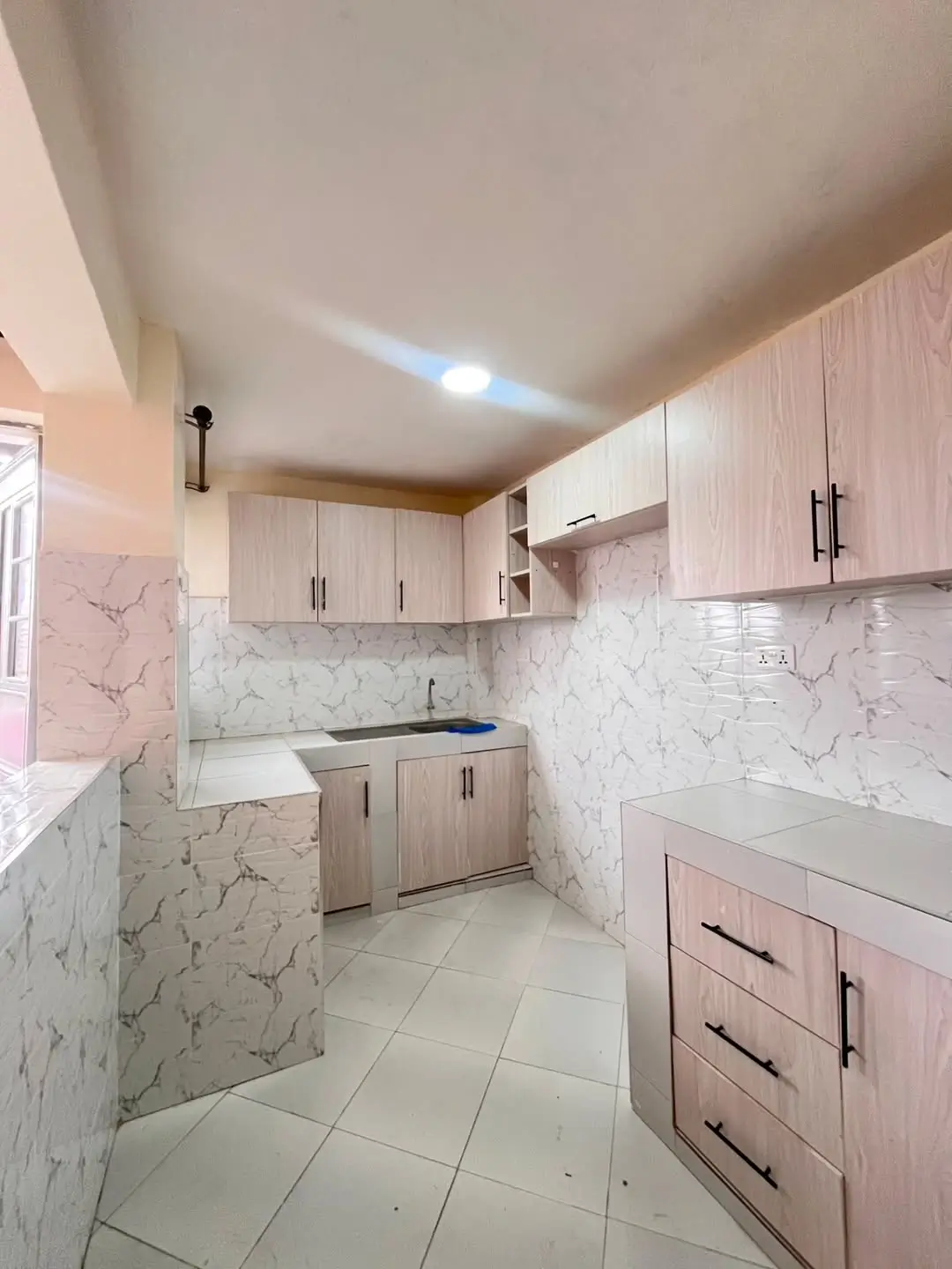 Modern kitchen with marble backsplash and light wood cabinetry