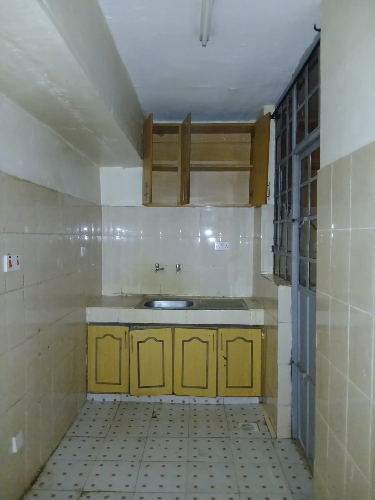 Compact kitchen with wooden cabinetry and white tile walls