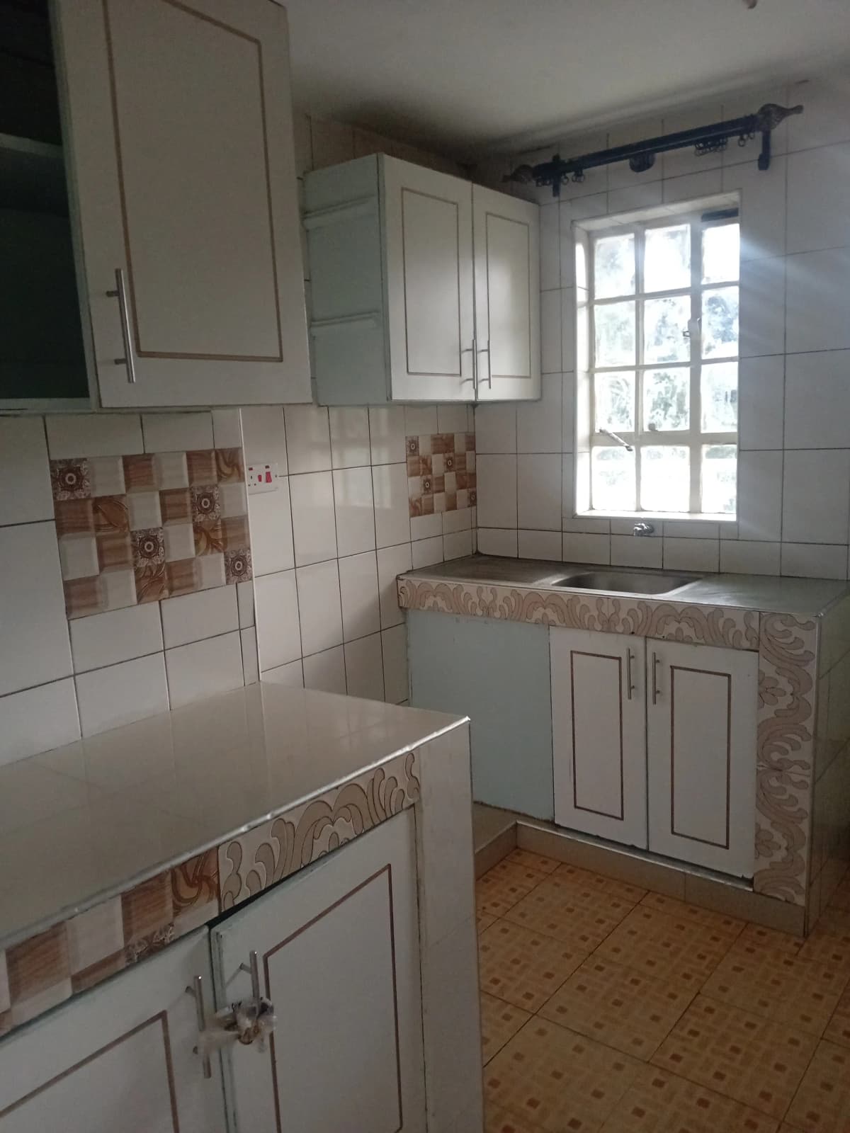 Compact kitchen with terracotta tile backsplash and natural light