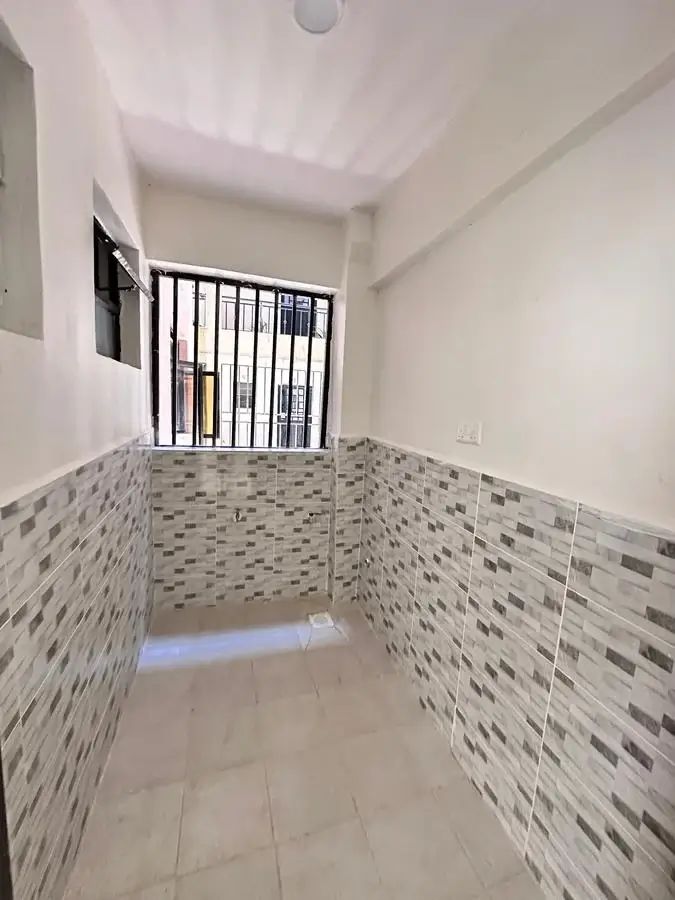 Utility room with mosaic tile walls and barred window