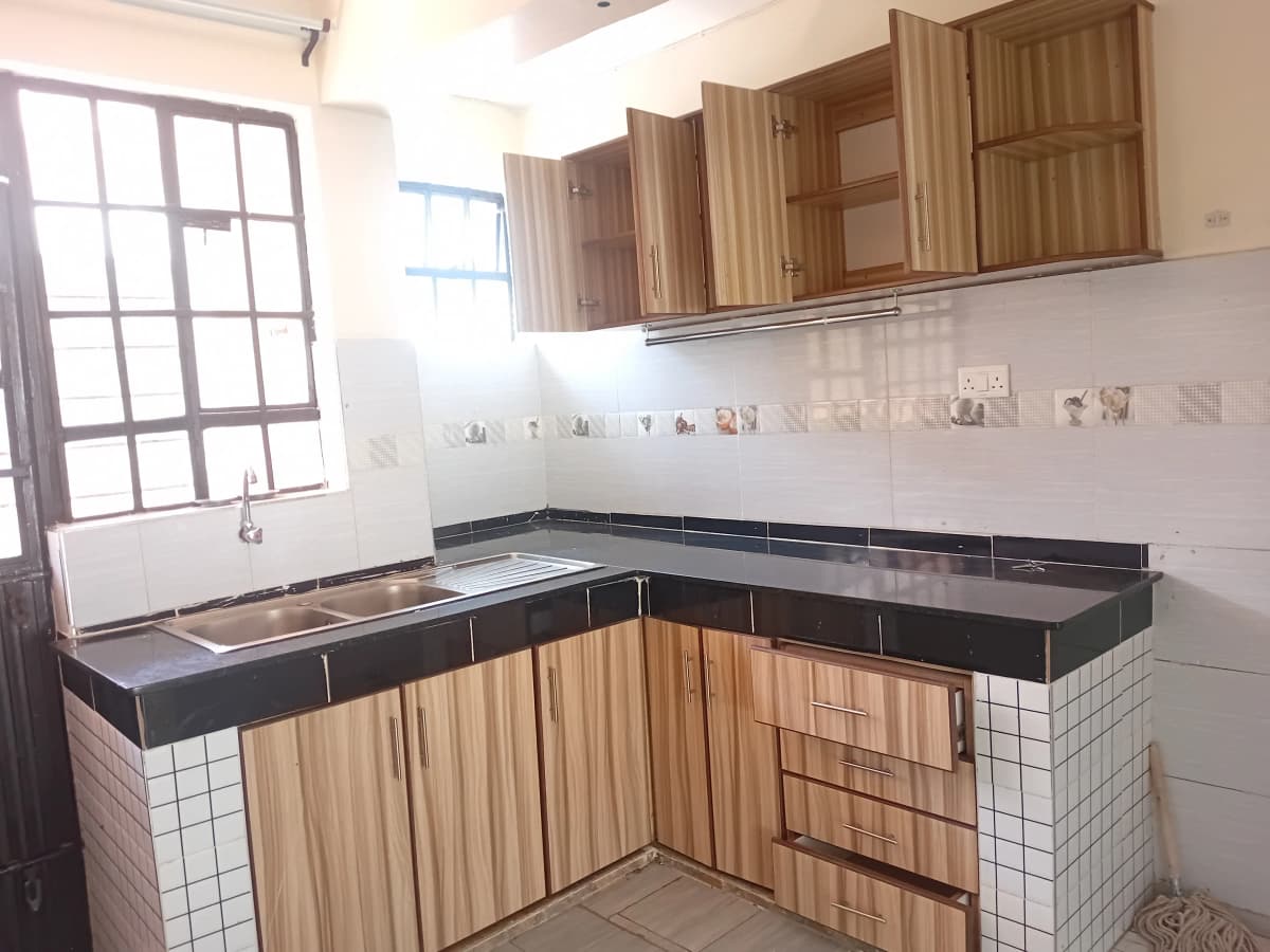 L-shaped kitchen with wooden cabinets and black countertops