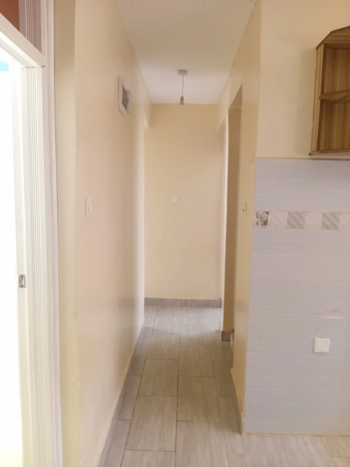 Narrow hallway with tile flooring and neutral walls