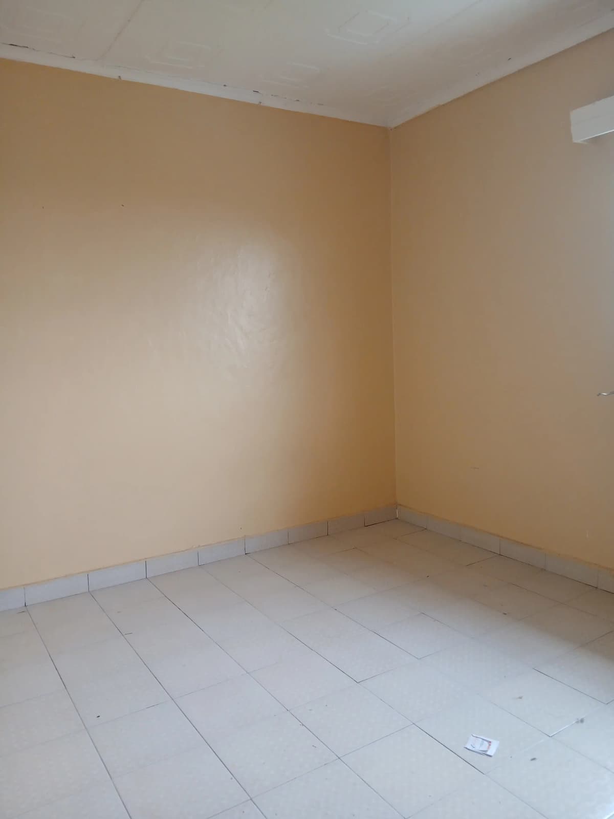 Empty bedroom with cream walls and light tile flooring