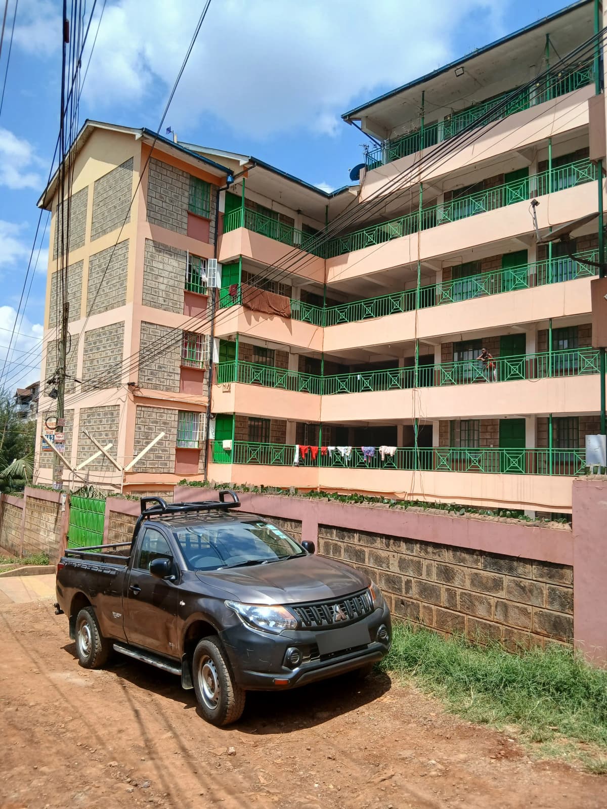Multi-story residential building with green balconies and parking