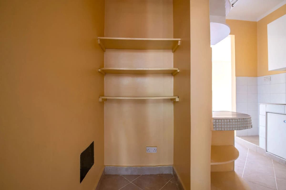 Compact pantry with open shelving and warm yellow walls