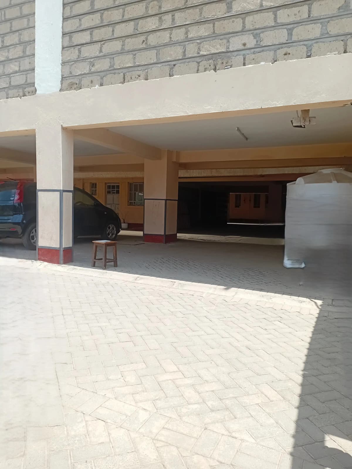 Ground-level covered parking bay with paved compound entrance