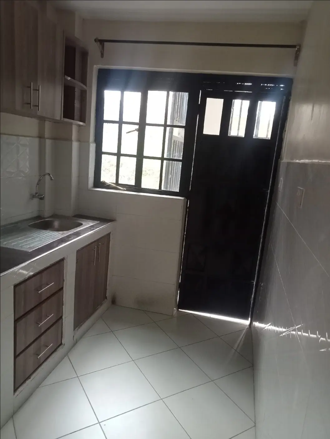 Compact kitchen with brown cabinetry and black door