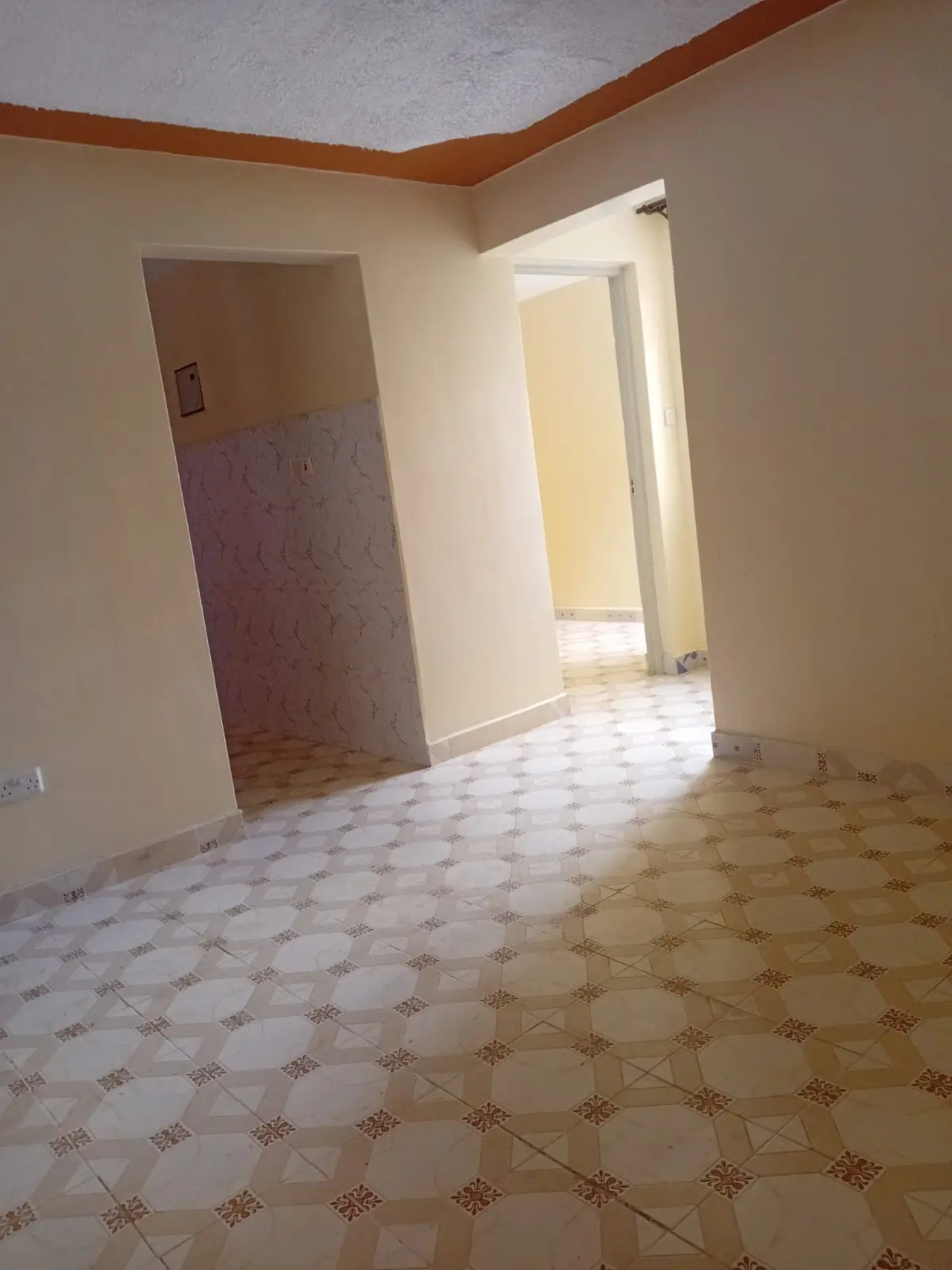 Empty living room with geometric tile flooring and wooden trim.