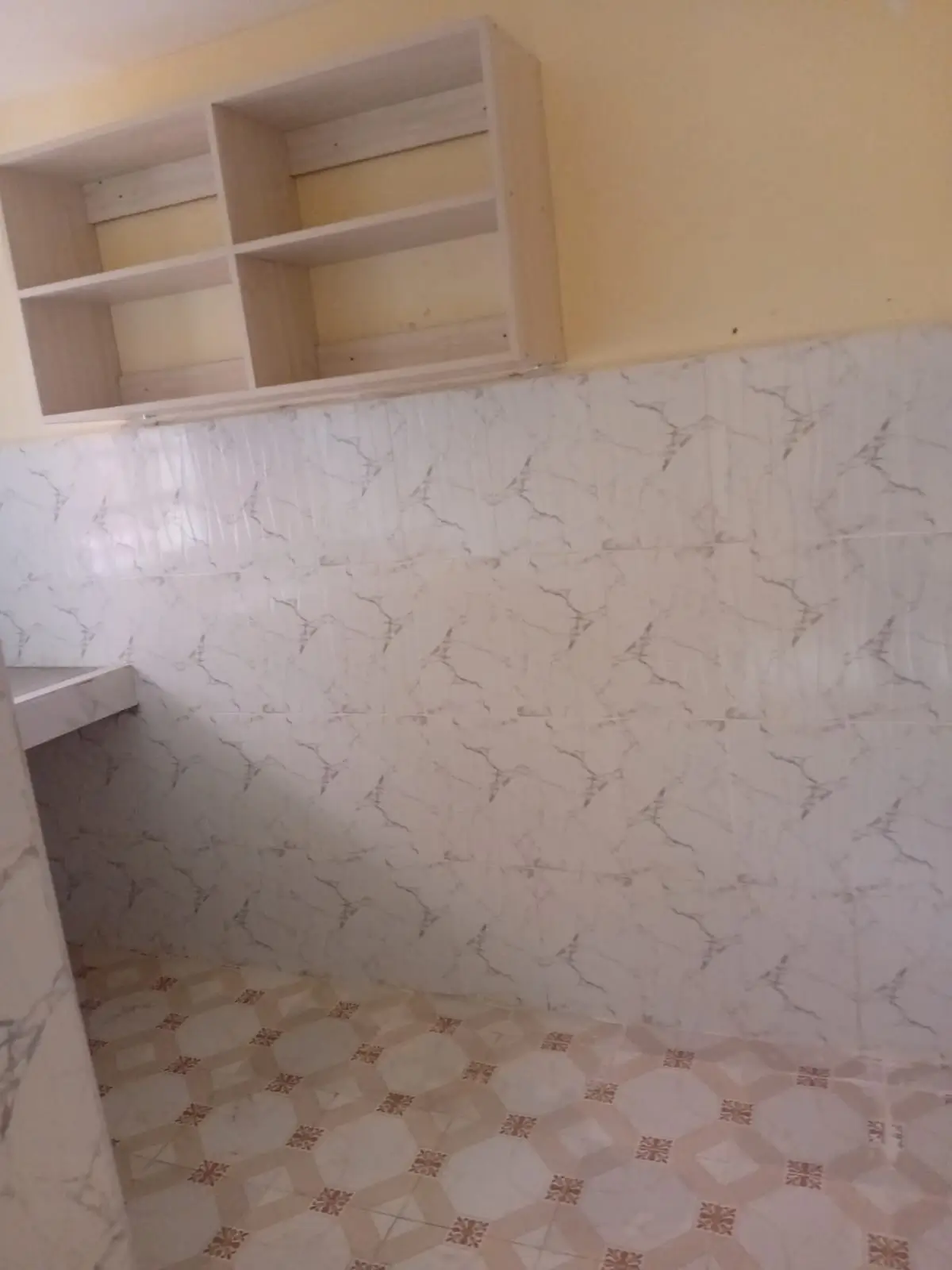Empty pantry with marble-pattern walls and shelving.