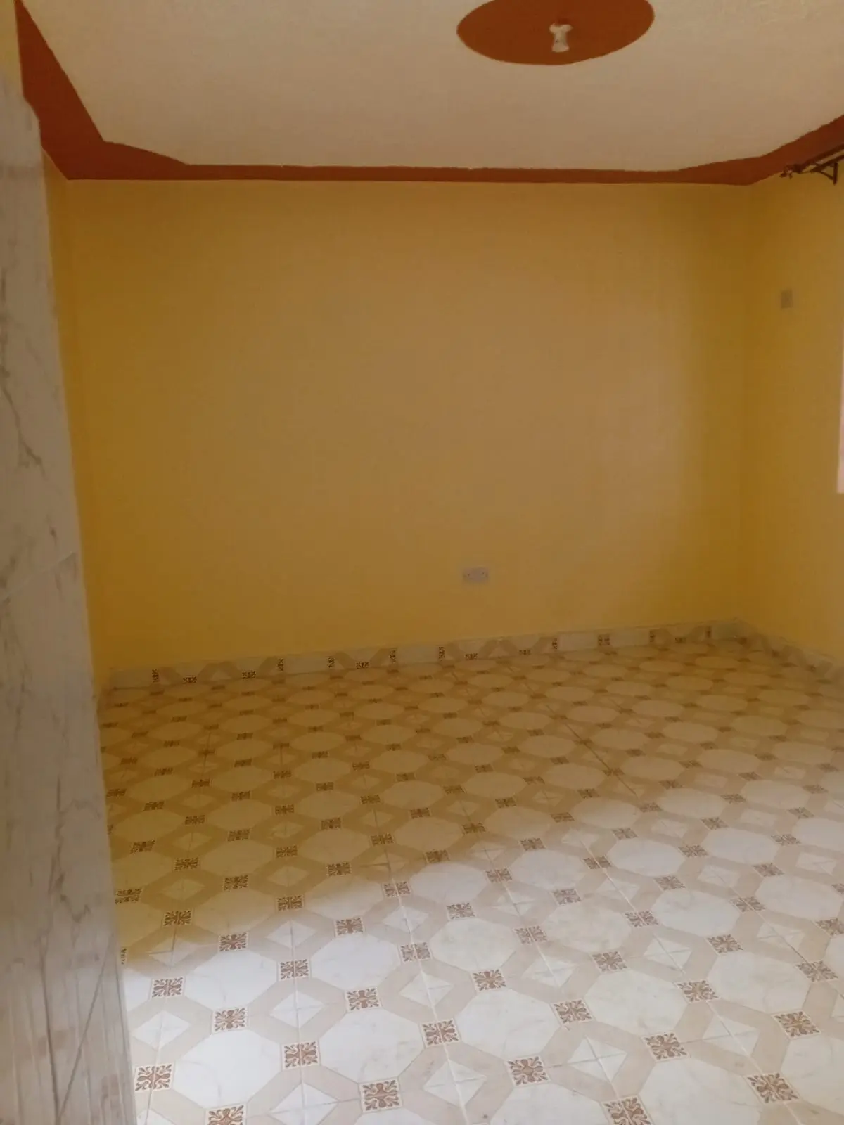 Empty bedroom with yellow walls and patterned tile floor