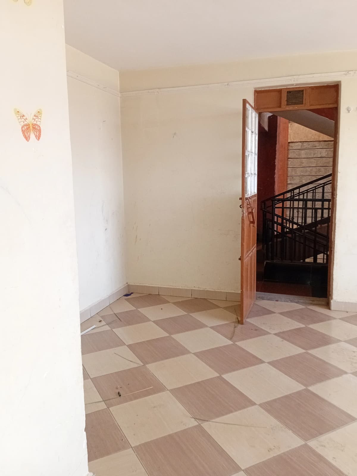 Empty hallway with checkered tile flooring and wooden doorway