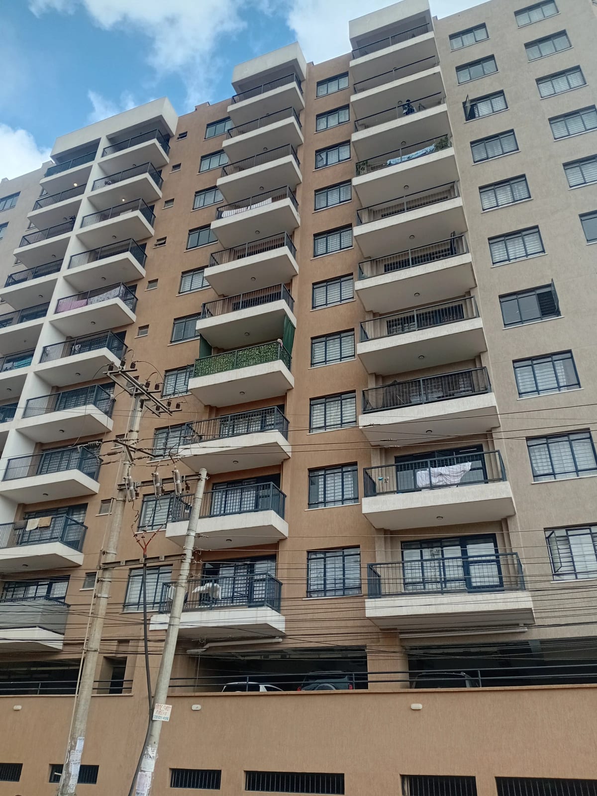 Multi-story residential building with balconies and ground-floor parking