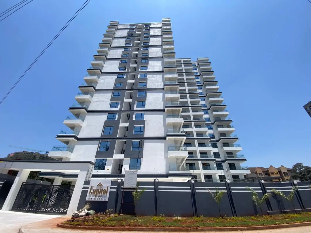 Modern multi-story residential building with balconies and secure perimeter fence